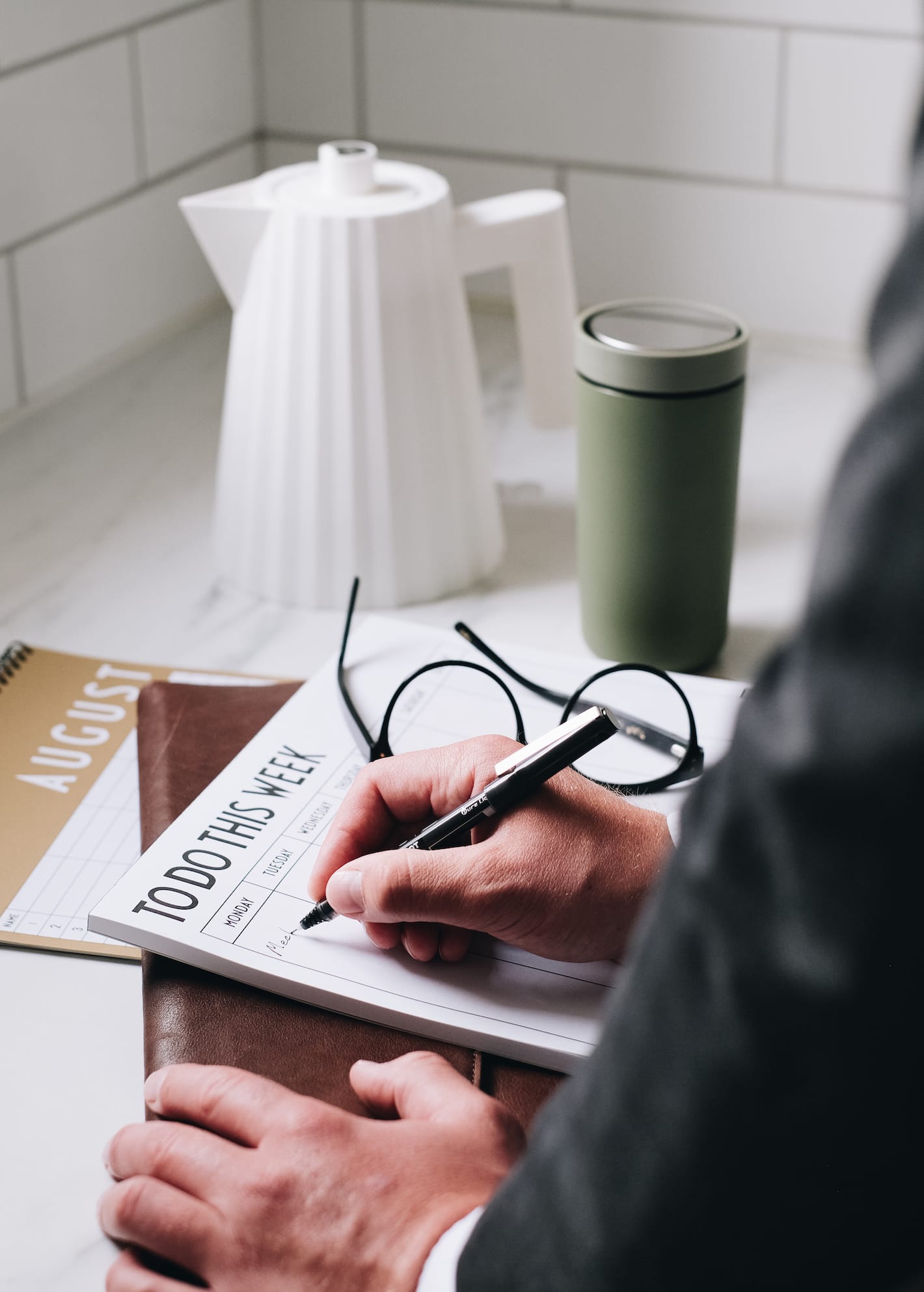 En mann i dress skriver et notat p&aring; en ukeskalender.