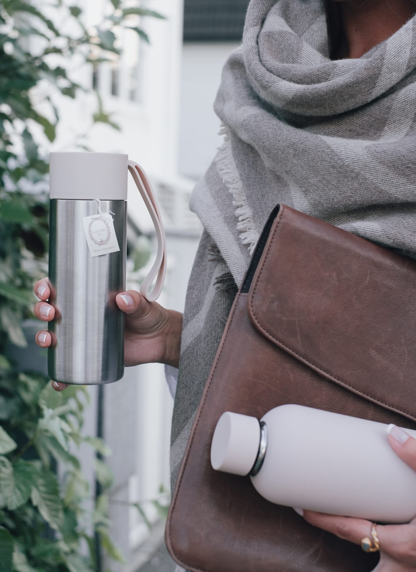 En person b&aelig;rer en termos, en drikkeflaske og en dokumentmappe.