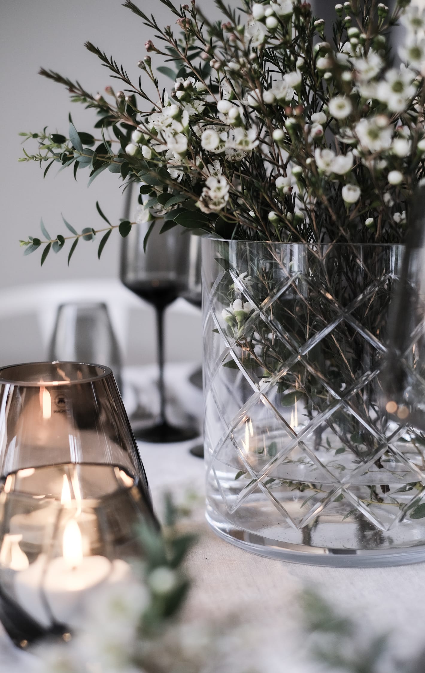 Magnor Skyline Lux lykt fylt med blomster p&aring; et dekket bord.